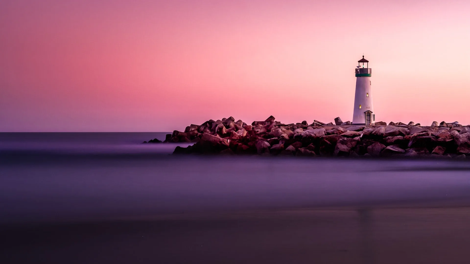 white lighthouse on rocky seashore